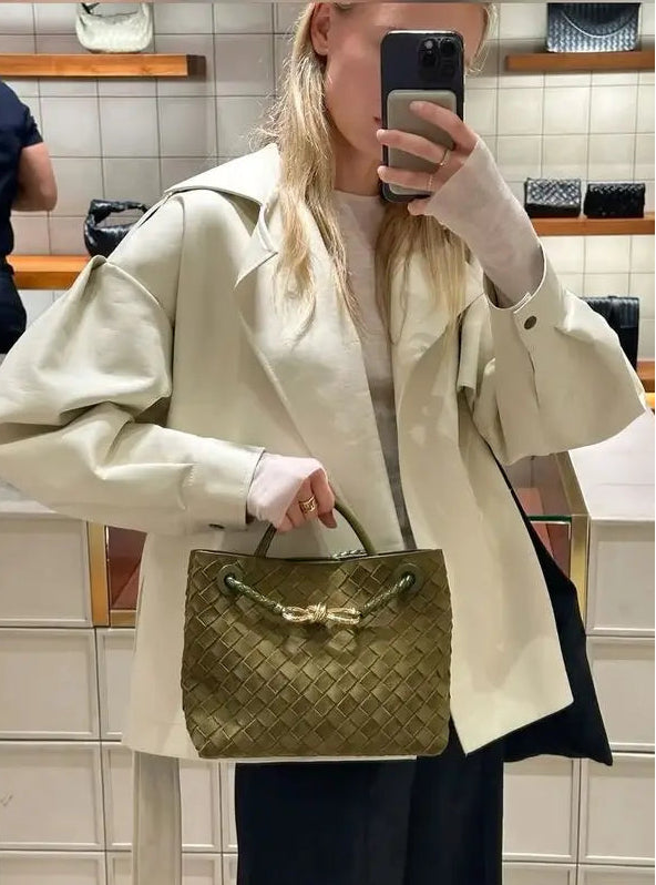 Person holding a woven handbag in a store setting
