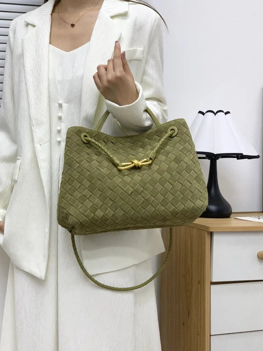 Person holding a green woven handbag indoors