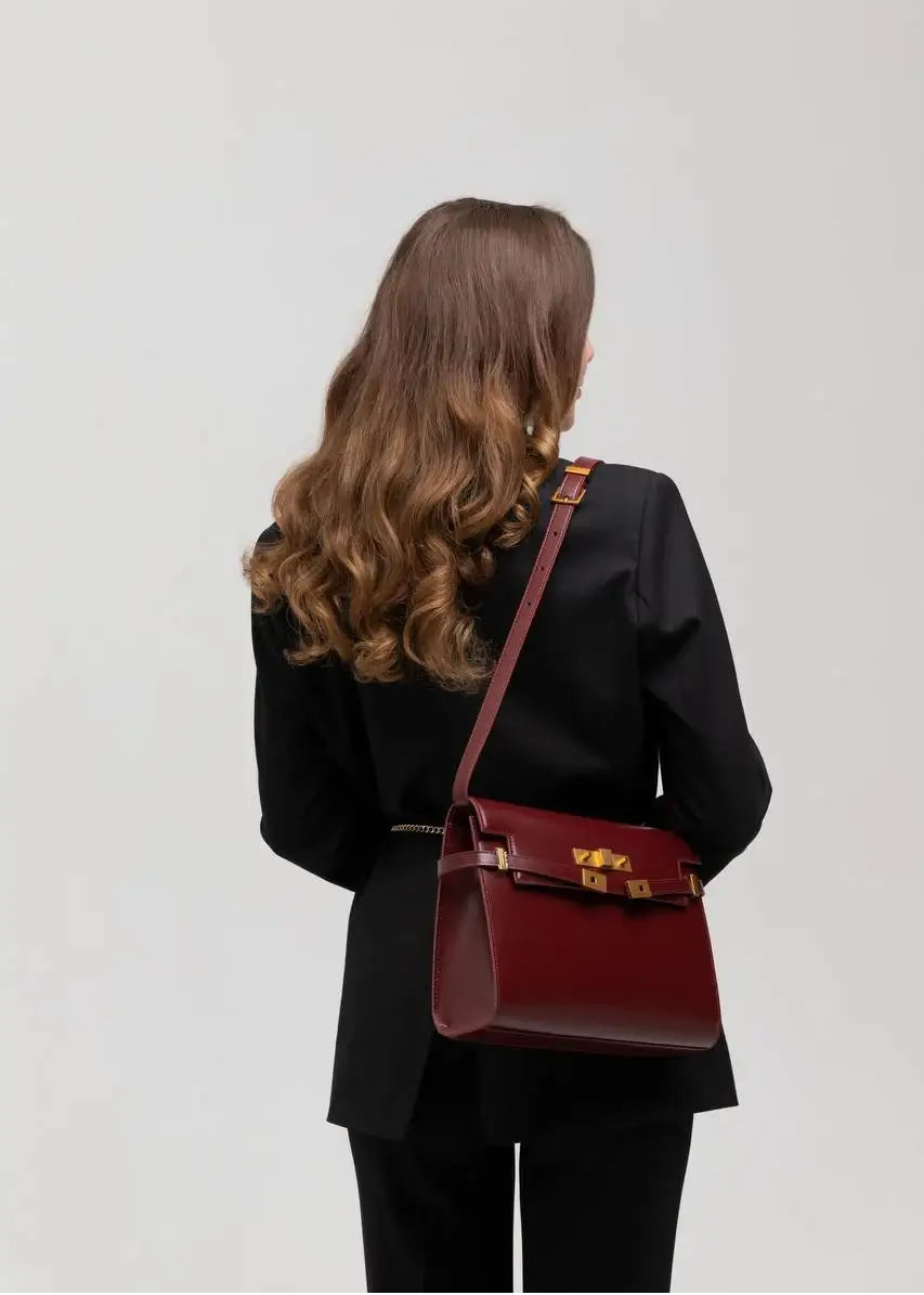 Woman carrying a red handbag on a plain background