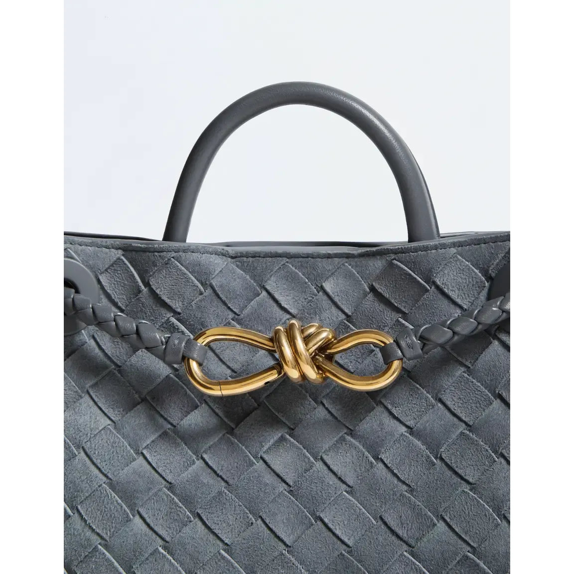 Gray woven handbag with a gold bow detail on a light gray background