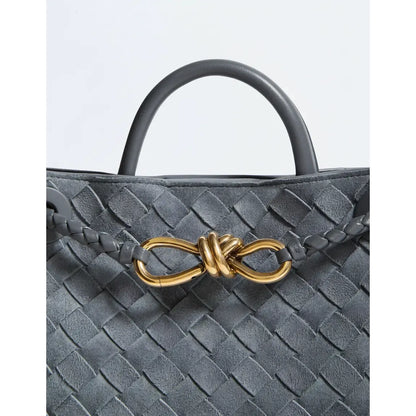 Gray woven handbag with a gold bow detail on a light gray background
