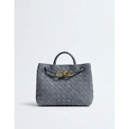 Gray woven handbag with a gold bow on a light gray background