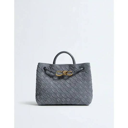 Gray woven handbag with a gold bow on a light gray background