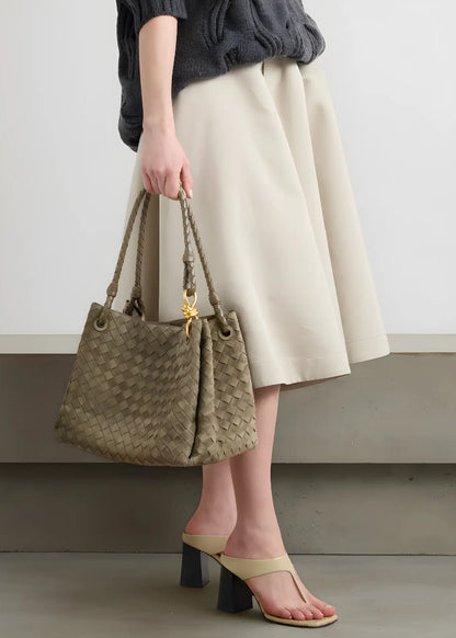Person holding a woven handbag with a plain background